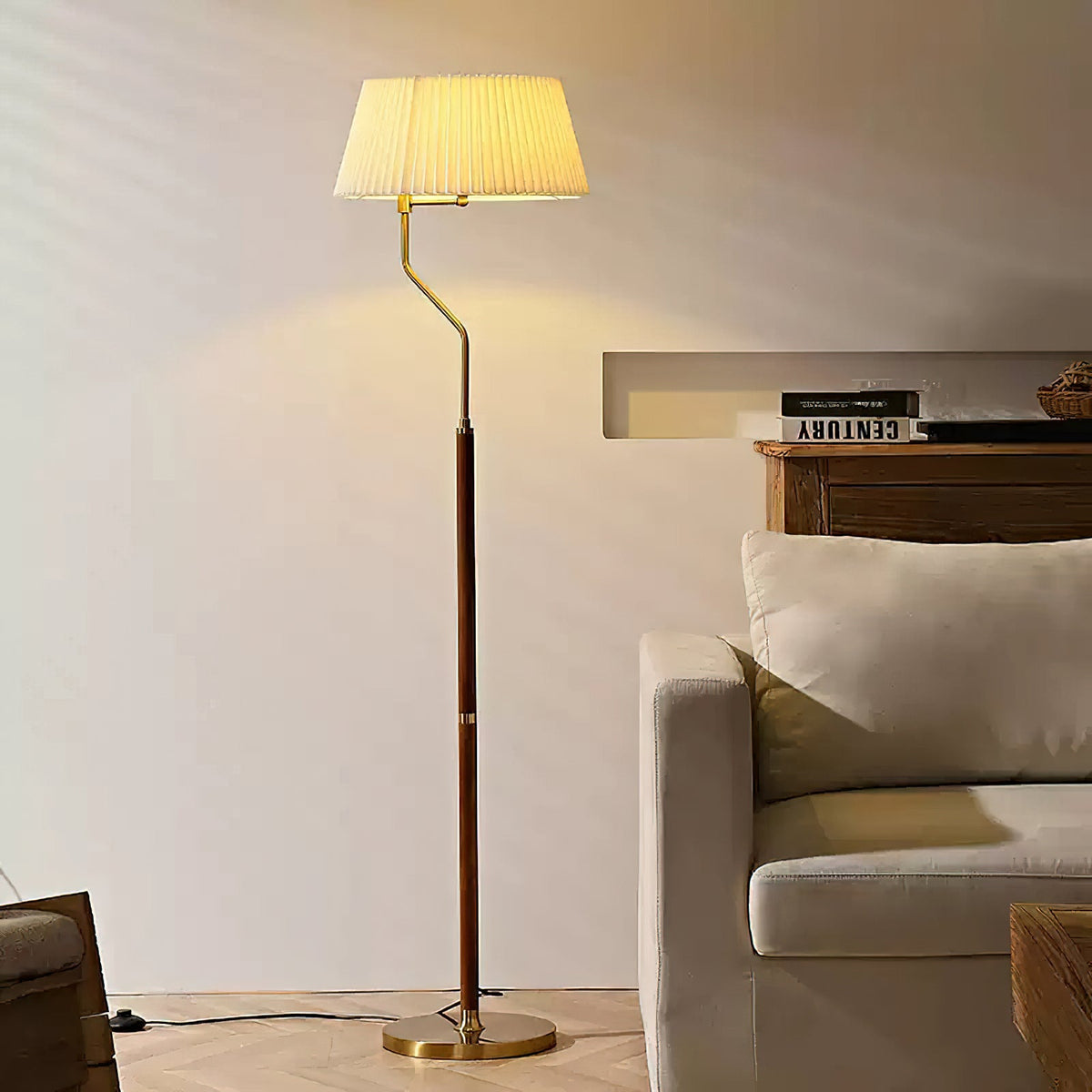 Lit Clérachic floor lamp with a pleated white shade, glowing beside a cream armchair on a herringbone floor.