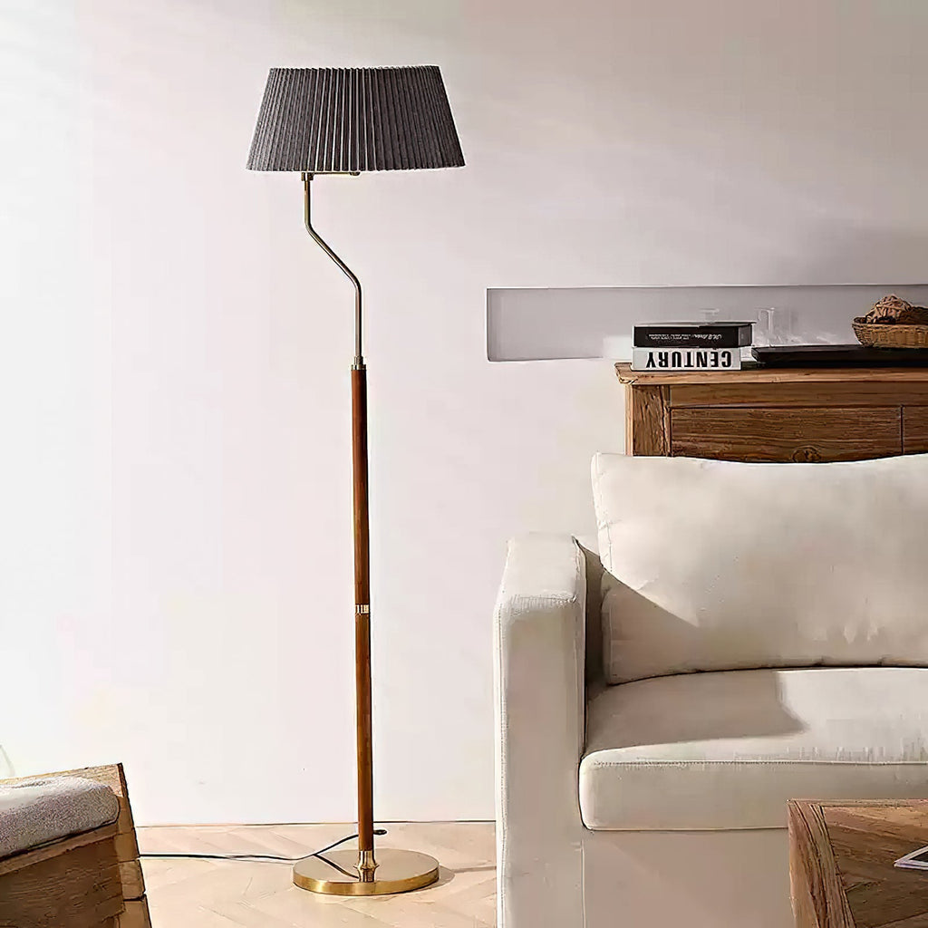 Dark grey pleated shade on a Clérachic floor lamp with a walnut stem, standing by a cream armchair and wood sideboard.