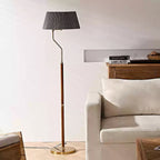 Dark grey pleated shade on a Clérachic floor lamp with a walnut stem, standing by a cream armchair and wood sideboard.