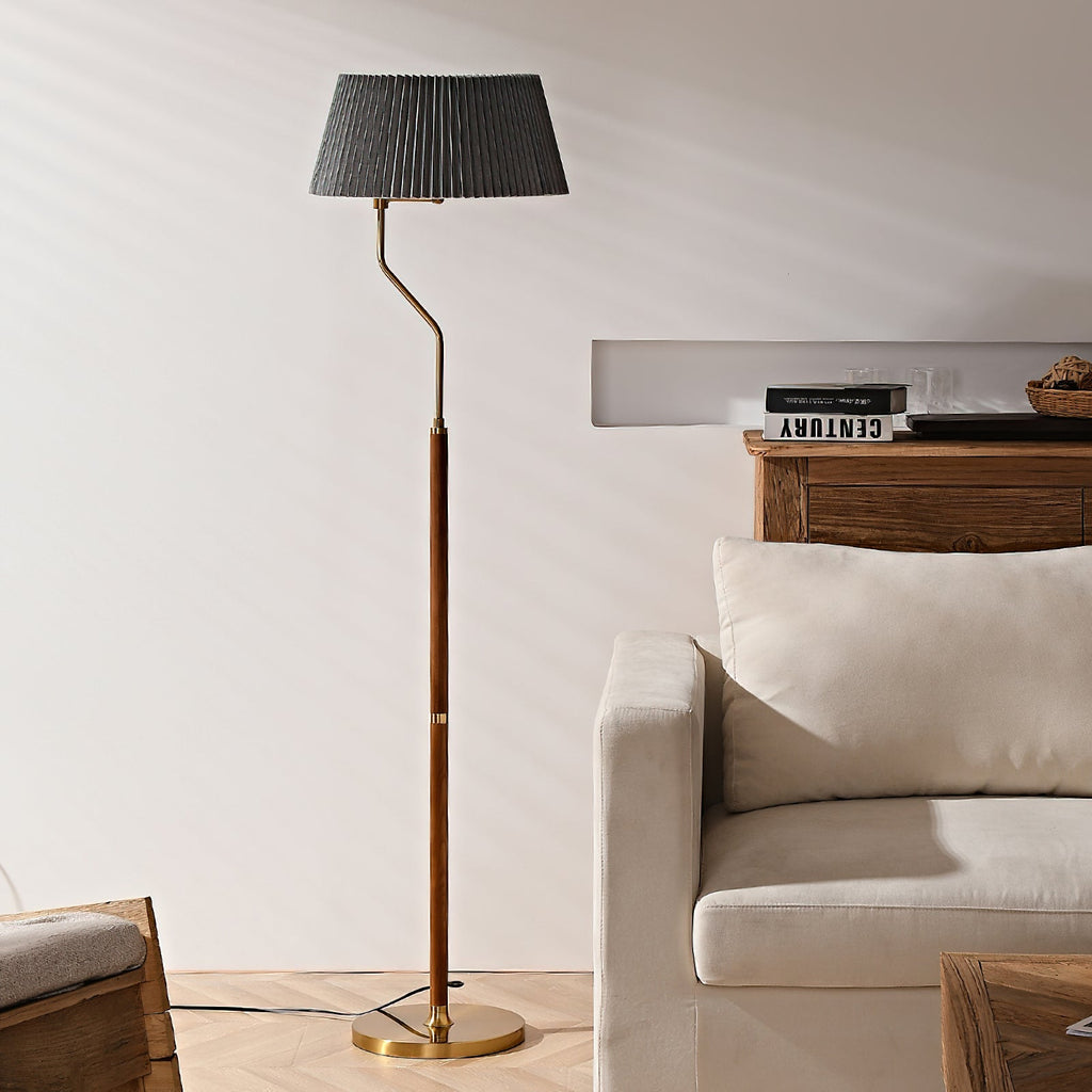 Unlit Clérachic floor lamp with a dark grey pleated shade, standing beside a cream armchair and a wooden console.
