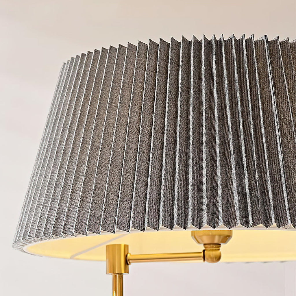 Close view of a wide pleated grey fabric shade and the brass swivel joint that holds it on this Clérachic floor lamp.