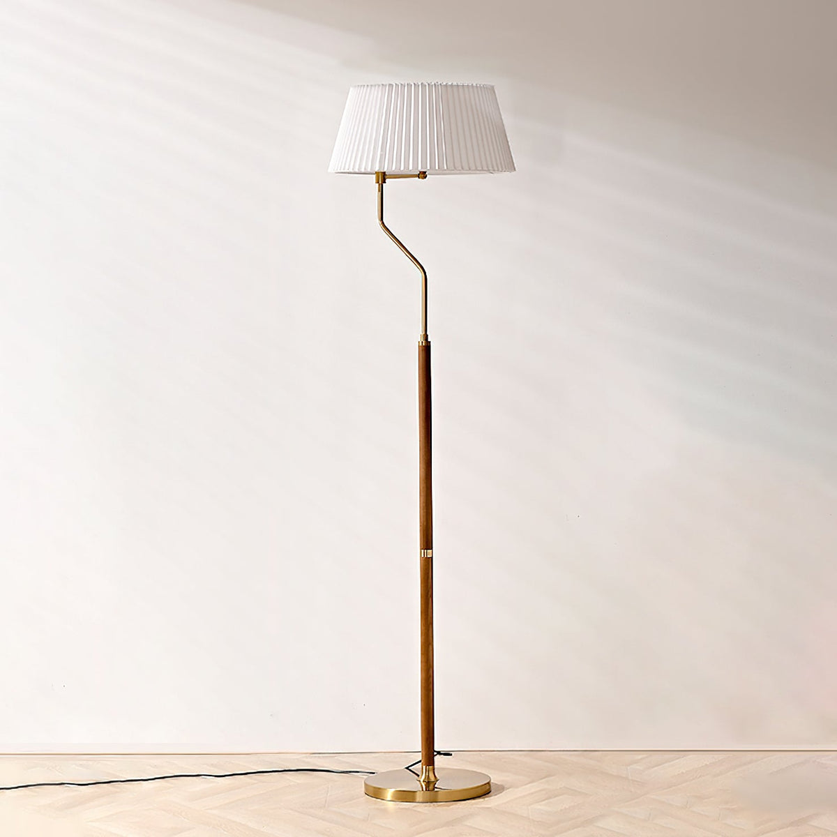A Clérachic floor lamp with a white pleated shade and slim walnut stem, standing on a pale herringbone floor.