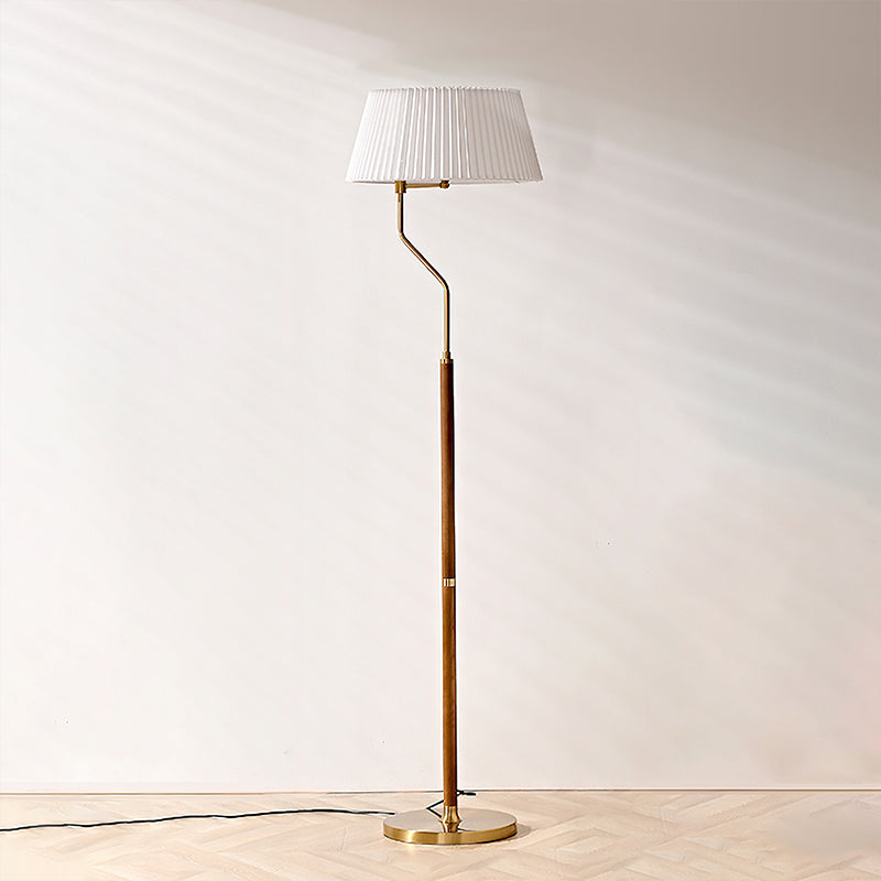 Full-length view of this Clérachic floor lamp with a white pleated shade and walnut stem, against a plain wall.