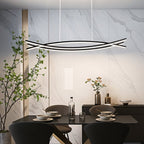 Clérachic black curved-bar LED chandelier on white cords above a dark dining table, in front of a veined marble wall.