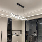 Clérachic black crossing-bar LED chandelier on black cords under a ceiling with a cove light, beside a glazed kitchen door.