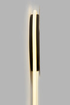 Side view of this Clérachic wall light, the dark disc standing off the grey wall while the LED loop glows warm behind it.