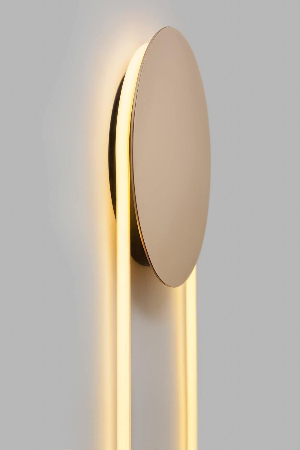Close side view of the gold disc on this Clérachic wall light, with warm light spilling along both sides of the LED loop.