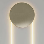 Close view of the matt champagne-gold disc on this Clérachic wall light, with warm light along the LED loop below.
