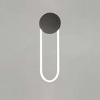 Front view of this Clérachic wall light on a soft grey backdrop, with a matte black disc and a white LED loop lit cool white.