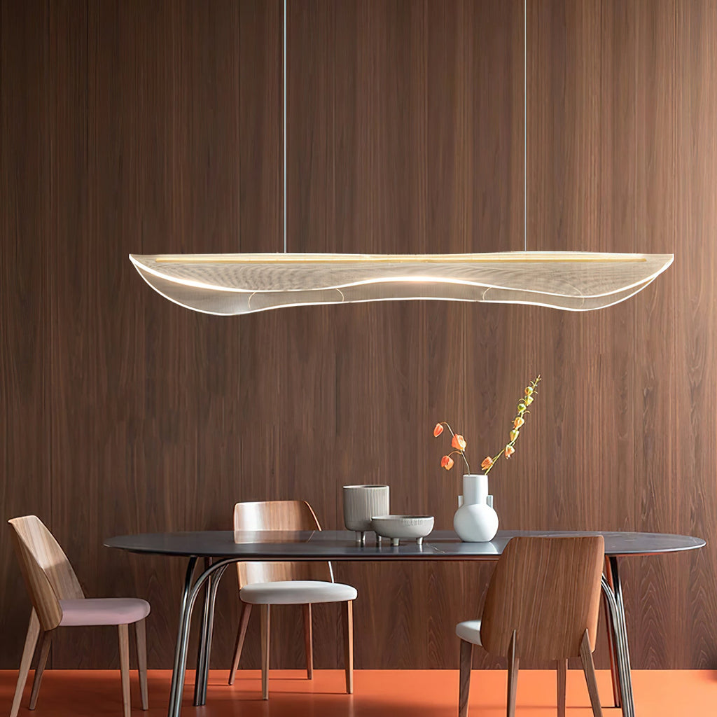 Clérachic acrylic pendant light hung against a walnut-panelled wall above a dark oval table with wooden chairs and a small vase.
