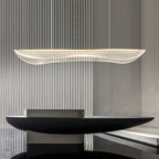 This Clérachic pendant light over a black sculptural console, with a ribbed grey wall behind its slim, wavy acrylic shade.