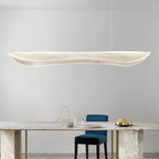 Clérachic wavy acrylic pendant hanging above a marble table with brass legs, a blue chair and a glass vase on a pale grey wall.