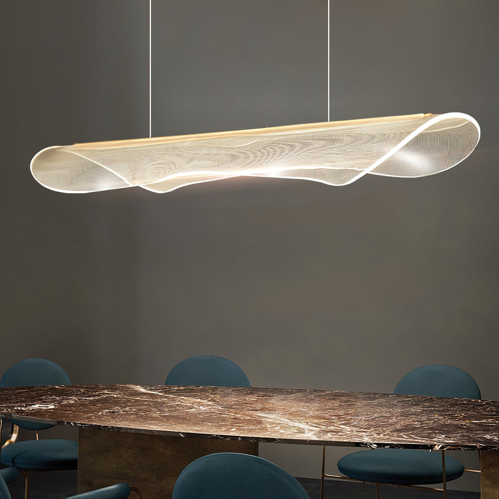 Angled view of a Clérachic pendant light with a curled, clear acrylic shade above a dark marble table and teal chairs.