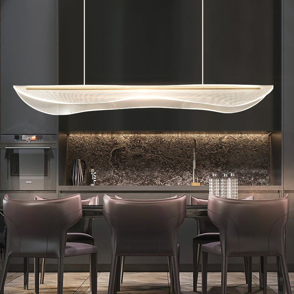 A Clérachic acrylic pendant light glowing above a dining table with plum leather chairs, in front of a dark kitchen with a stone splashback.