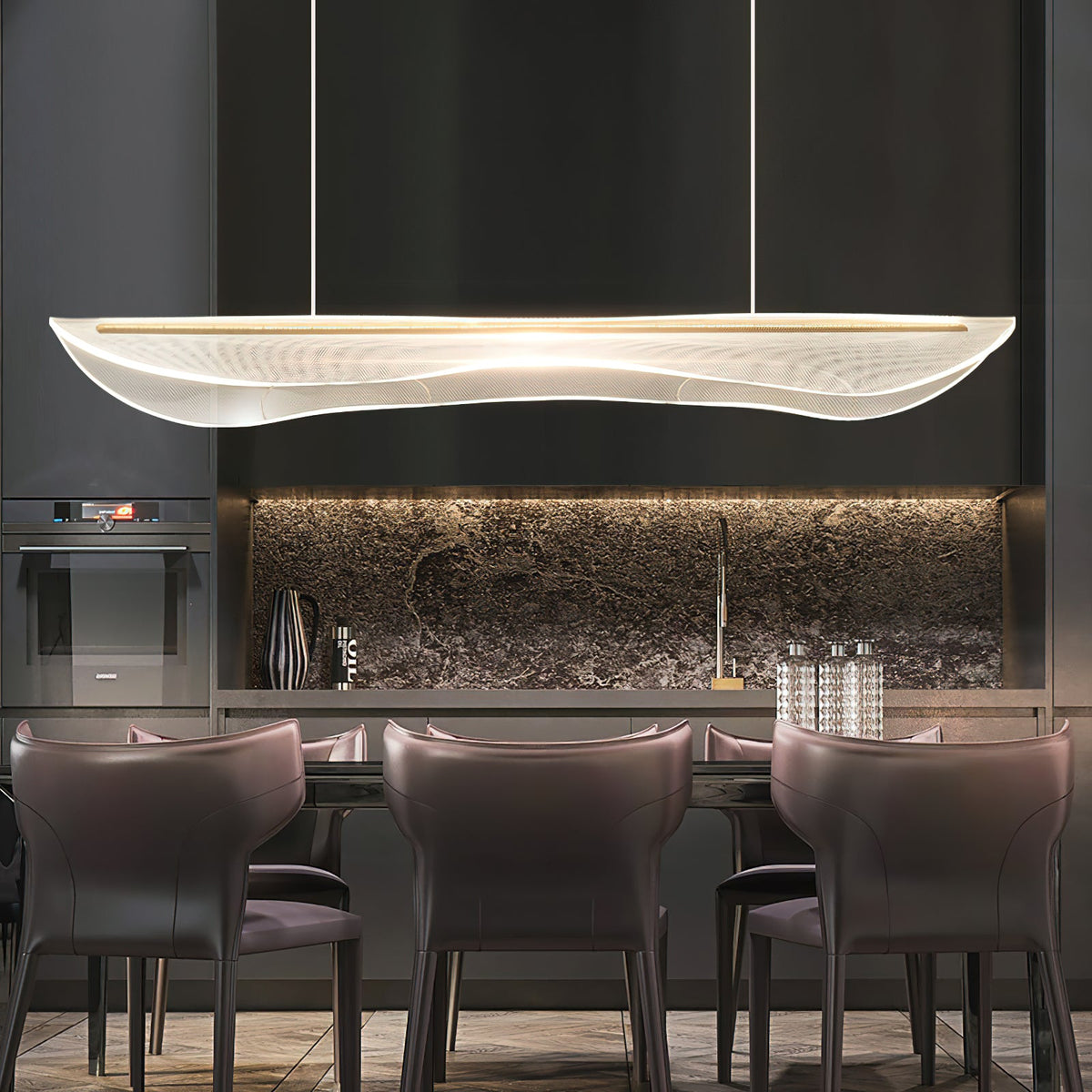 A Clérachic acrylic pendant light glowing above a dining table with plum leather chairs, in front of a dark kitchen with a stone splashback.