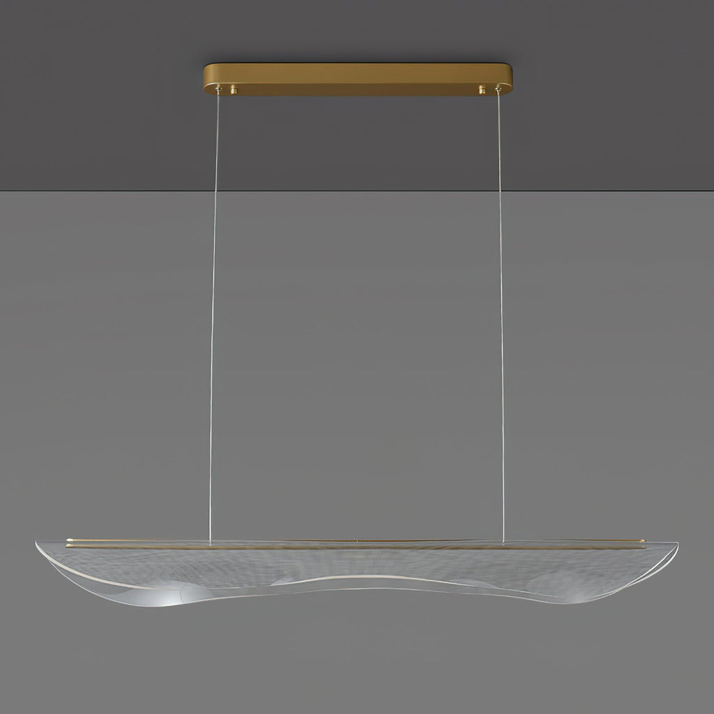 Clérachic pendant light, unlit, with the gold canopy at the ceiling and a long clear acrylic shade hanging on thin cables.