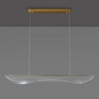 Clérachic pendant light, unlit, with the gold canopy at the ceiling and a long clear acrylic shade hanging on thin cables.