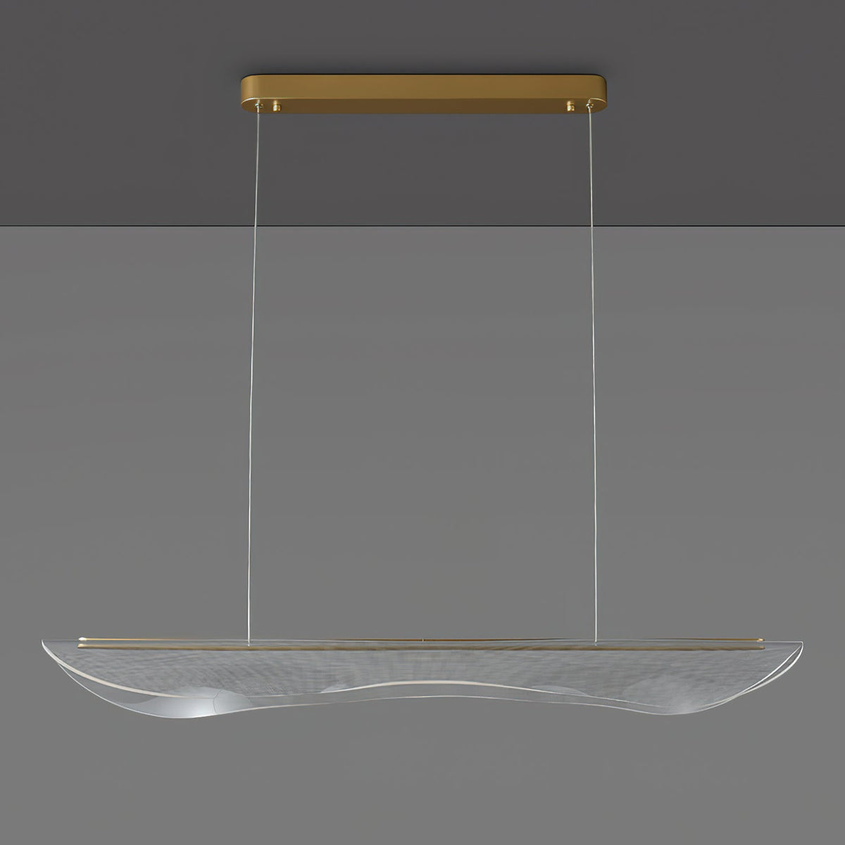 Clérachic pendant light, unlit, with the gold canopy at the ceiling and a long clear acrylic shade hanging on thin cables.