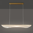Lit Clérachic linear pendant with a long drop on thin cables, its clear acrylic shade glowing warm along the centre.
