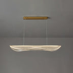 Clérachic linear pendant with a warm light along the rim of its wavy acrylic shade, hung under a gold canopy against grey.