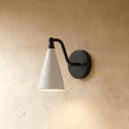 Clérachic cone-shade wall sconce in matte black with a white shade, mounted on a plaster wall in studio light.