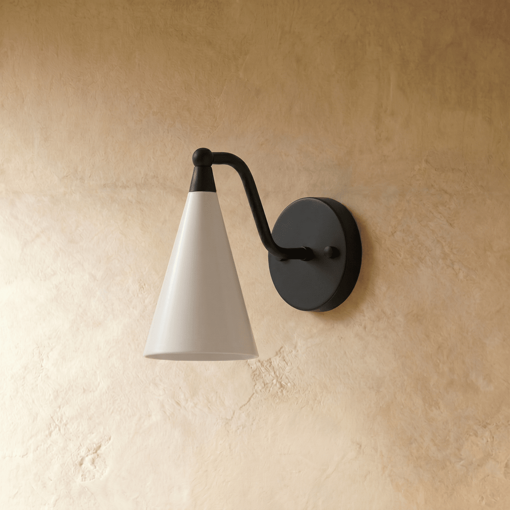 Clérachic cone-shade wall sconce in matte black, shown from a slightly closer studio angle on a plaster wall.