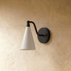 Clérachic cone-shade wall sconce in matte black, shown from a slightly closer studio angle on a plaster wall.