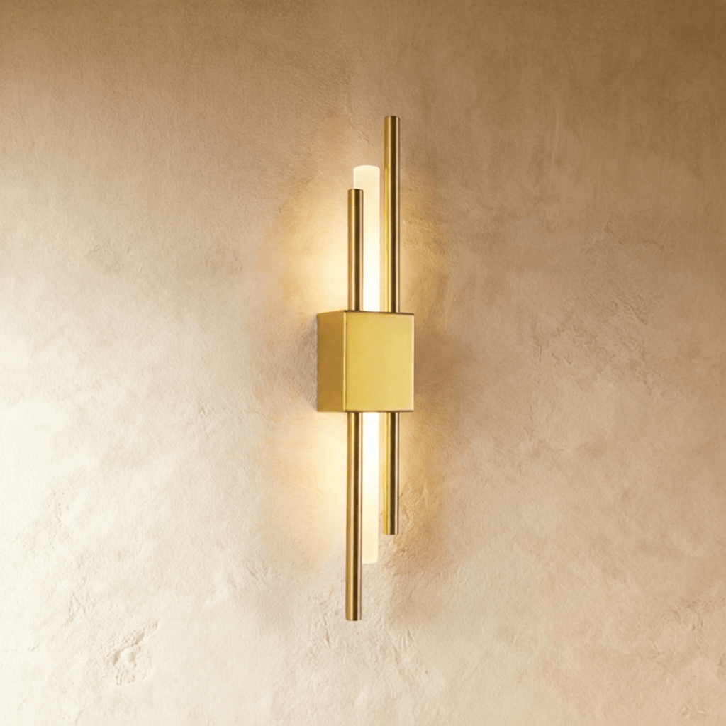 Lit from within, the Clérachic wall sconce in gold sends warm light along its acrylic diffuser between two brass rods.