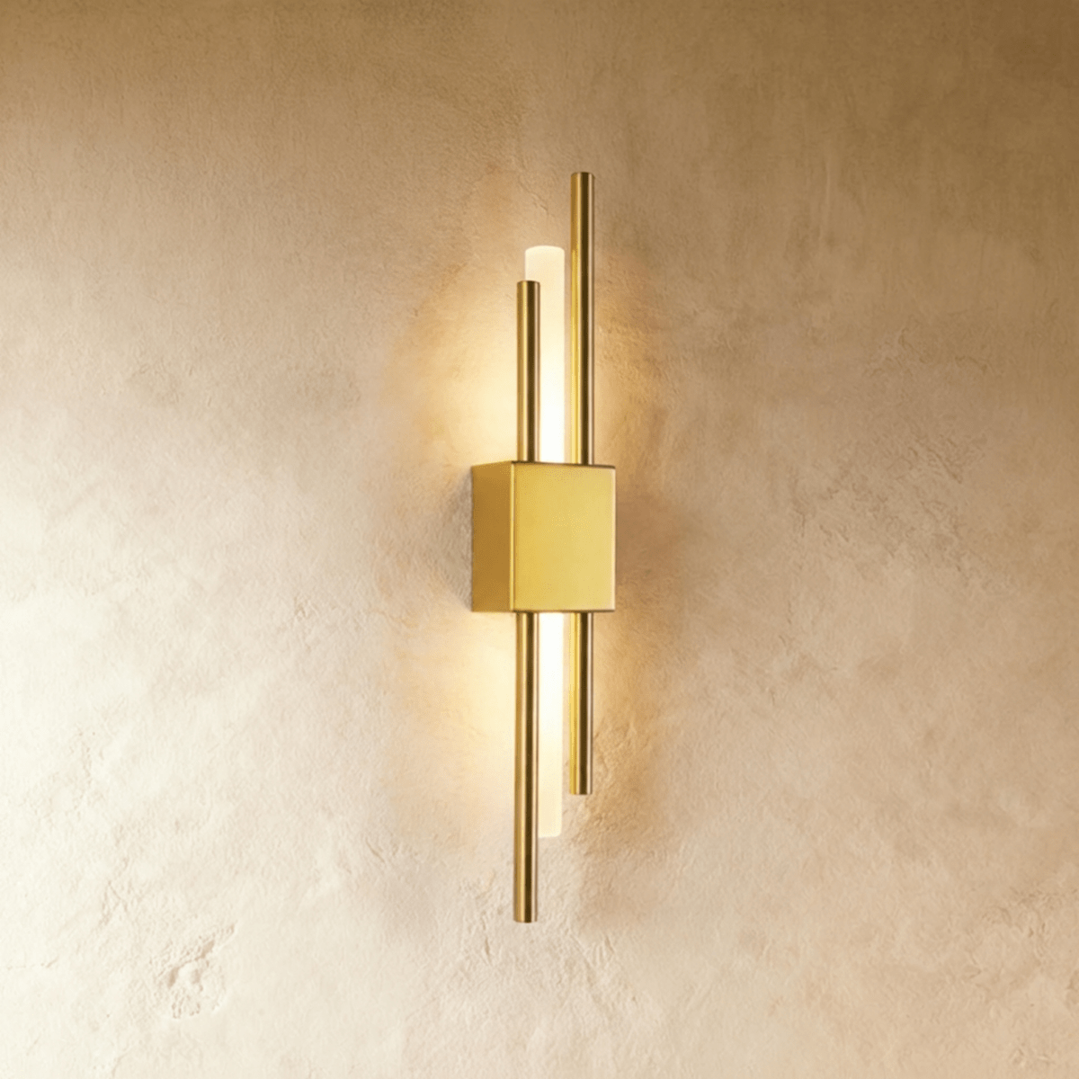 Lit from within, the Clérachic wall sconce in gold sends warm light along its acrylic diffuser between two brass rods.