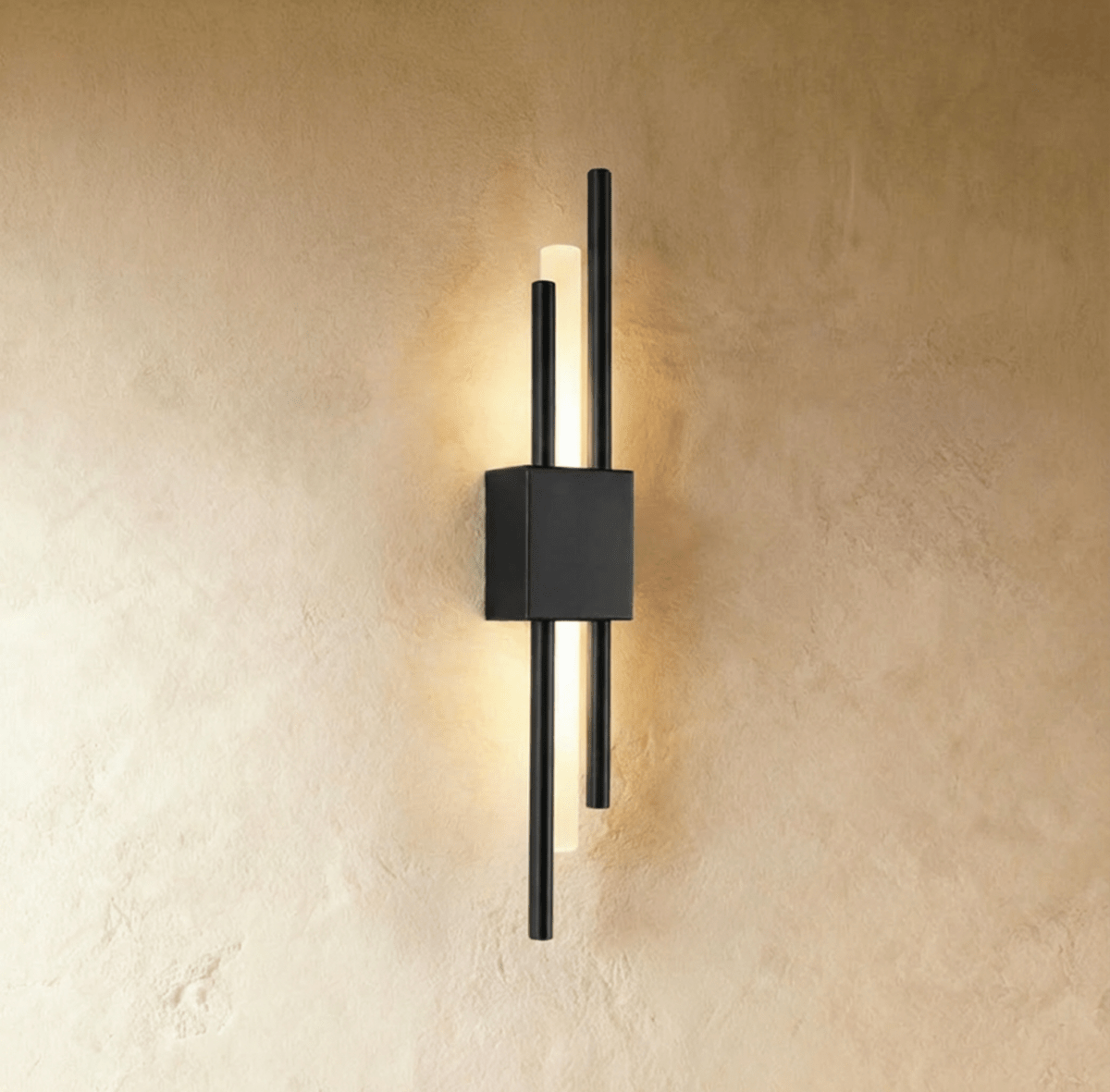A closer view of the matte black Clérachic wall sconce, its square backplate anchoring two rods and a lit acrylic diffuser.