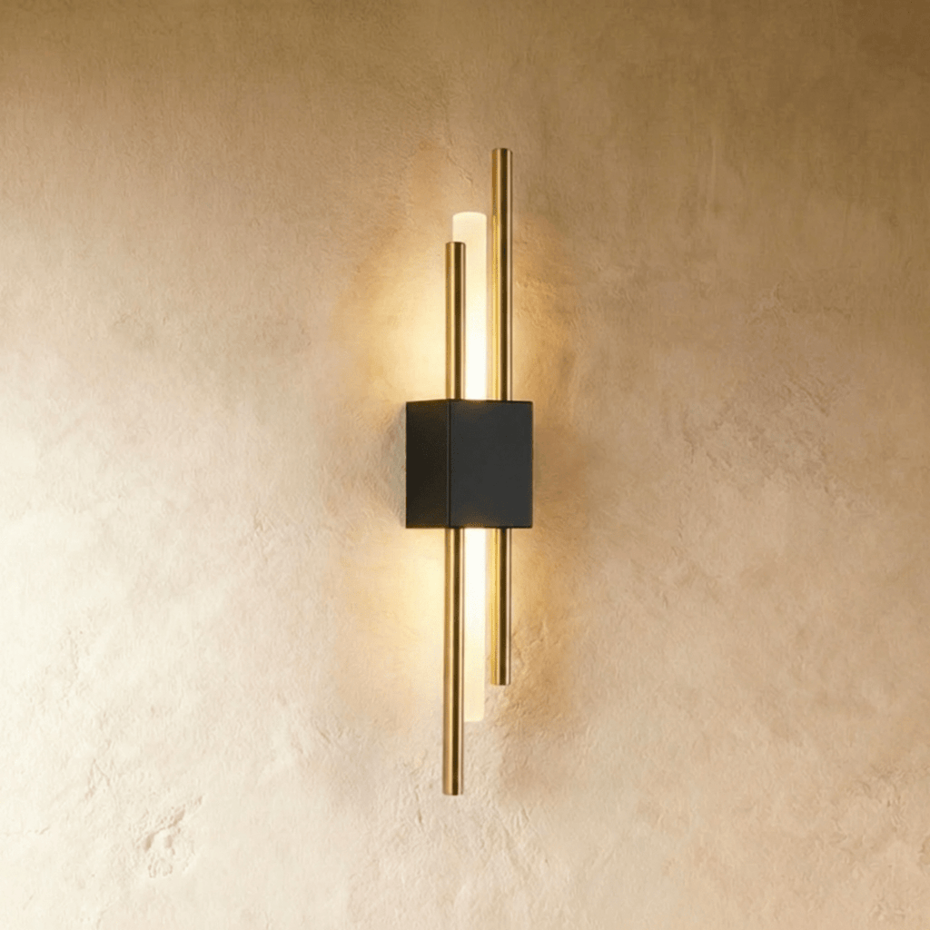 This Clérachic wall sconce combines a black backplate with brushed gold rods around a softly lit acrylic diffuser.