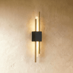 This Clérachic wall sconce combines a black backplate with brushed gold rods around a softly lit acrylic diffuser.