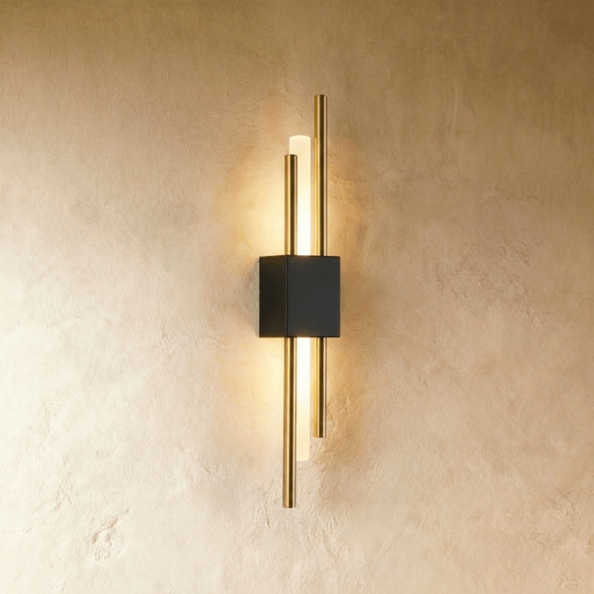 This Clérachic wall sconce combines a black backplate with brushed gold rods around a softly lit acrylic diffuser.