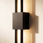 An extreme close-up of the Clérachic wall sconce's black square backplate, where two rods cross the lit acrylic strip.