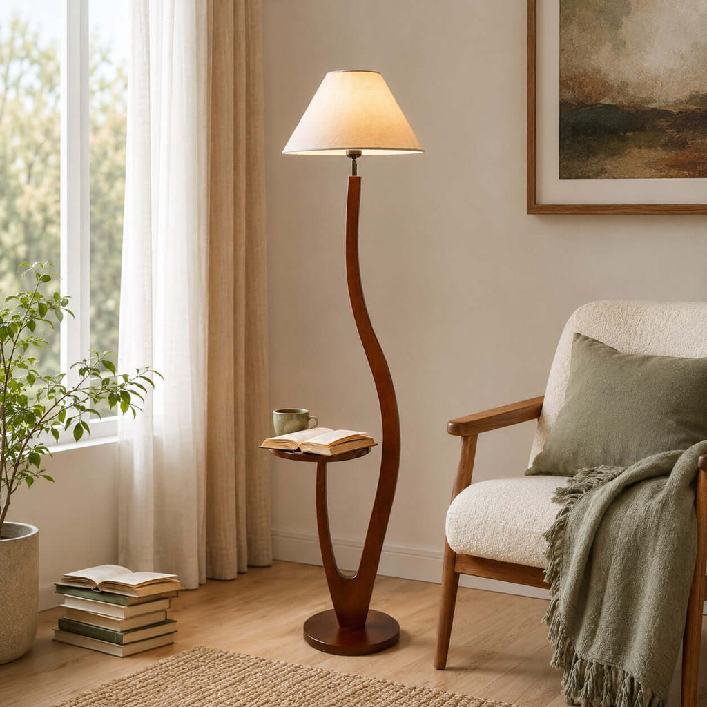 A cream tapered shade on this Clérachic floor lamp stands by a sunny window, with an open book and a cup resting on its tray.