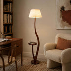 Next to a wooden desk and bookshelf, this Clérachic floor lamp's textured white shade lights a boucle armchair with a rust cushion.