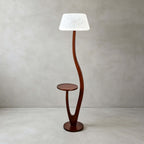 The version with a rounded white textured shade stands on a pale floor against a plaster wall, this Clérachic floor lamp lit softly.