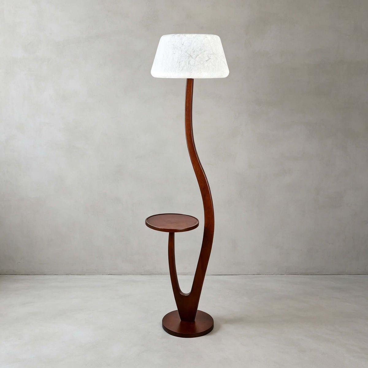 The version with a rounded white textured shade stands on a pale floor against a plaster wall, this Clérachic floor lamp lit softly.