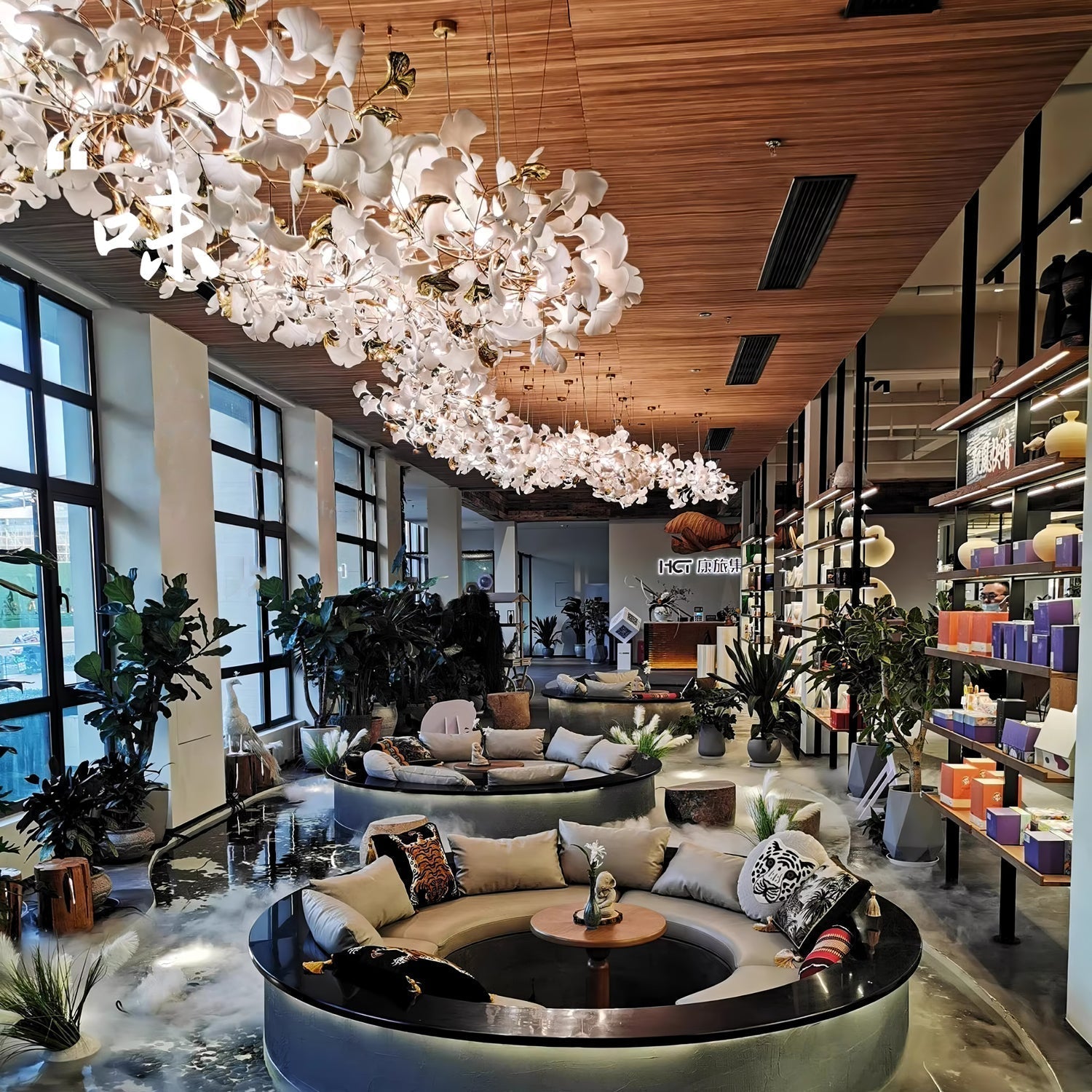The Clérachic gingko chandelier running the length of a showroom ceiling above circular seating.