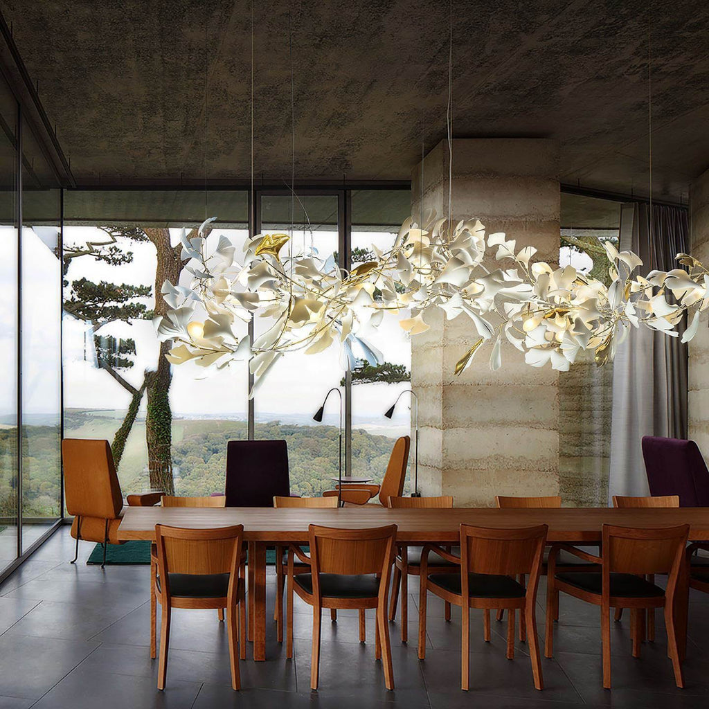 The Clérachic gingko chandelier lit above a timber dining table with a valley view beyond.