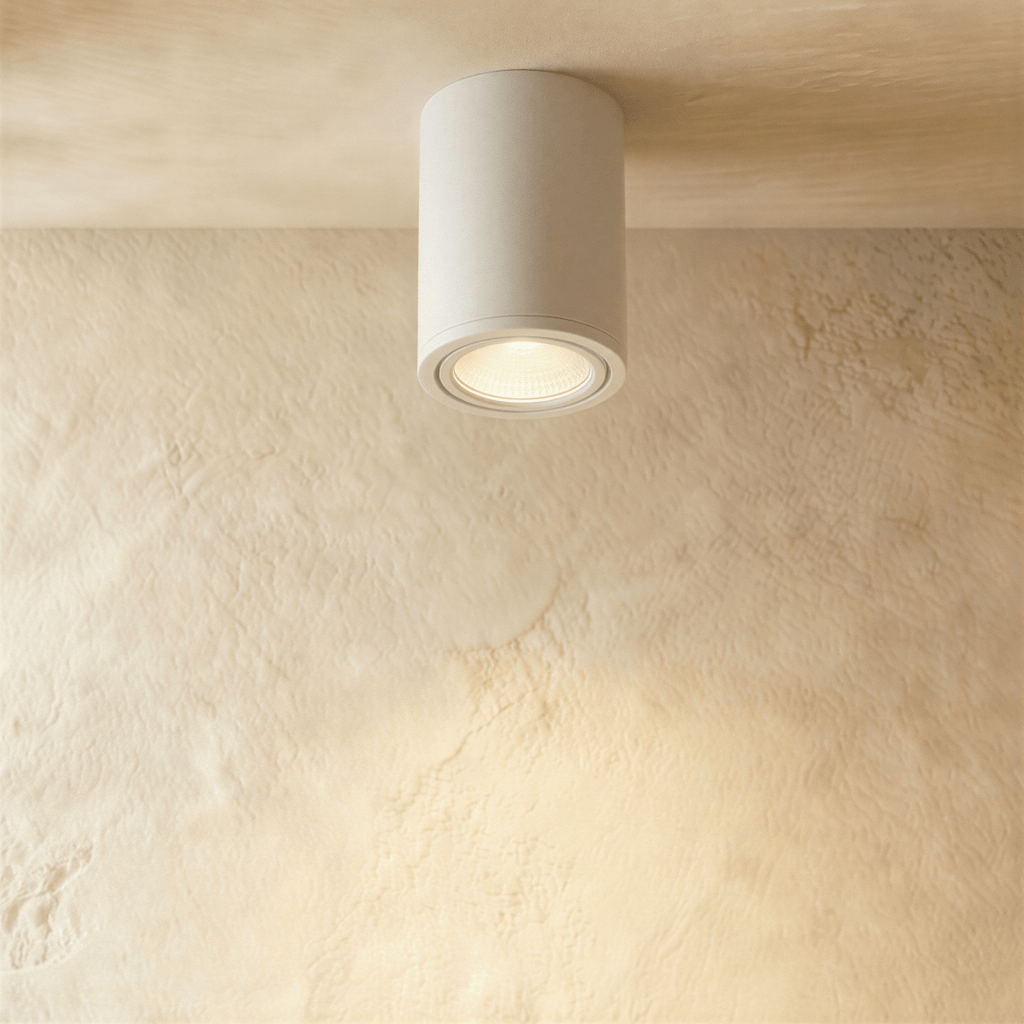 Clérachic compact white cylinder downlight, lit warm and mounted flush against a plastered ceiling.