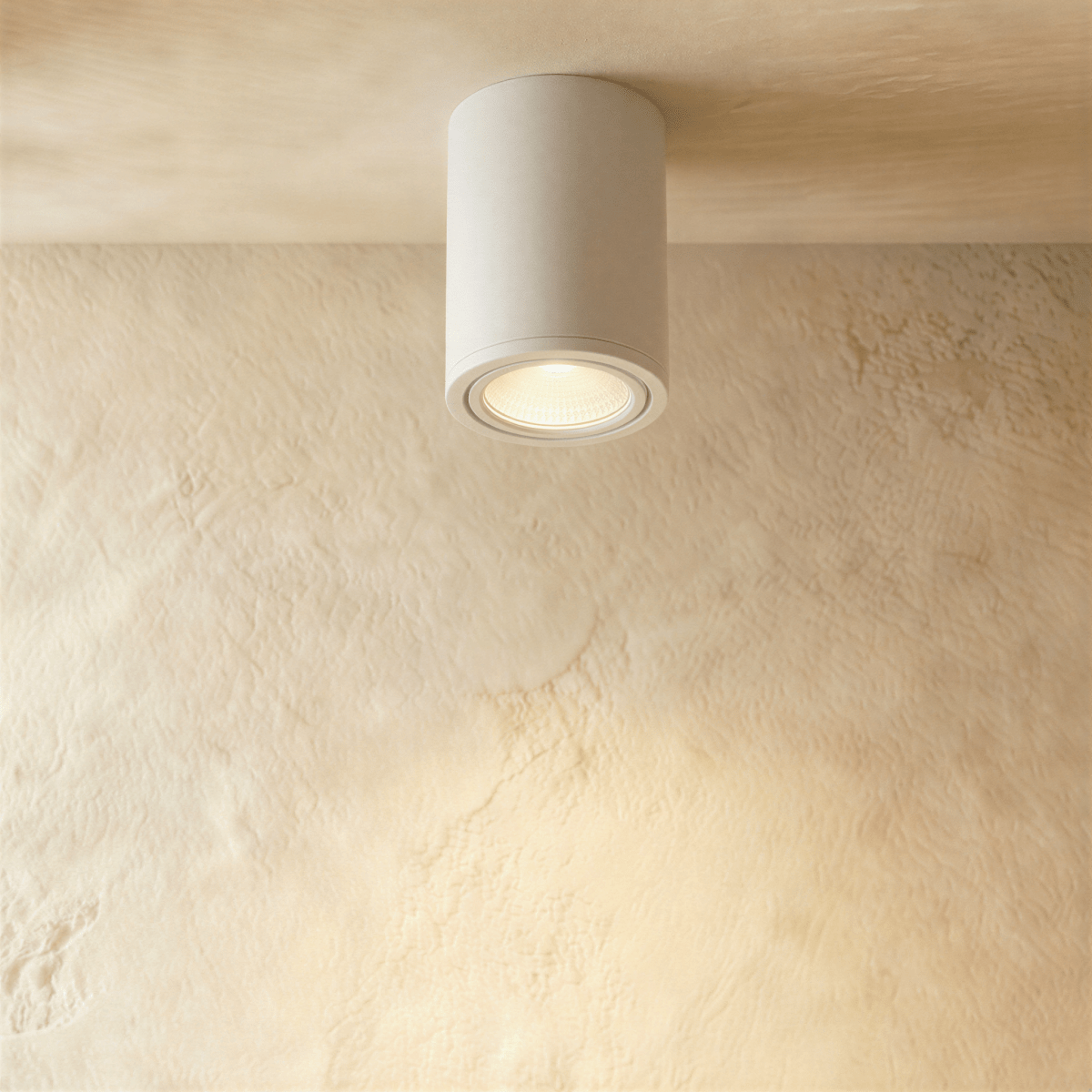 Clérachic compact white cylinder downlight, lit warm and mounted flush against a plastered ceiling.