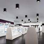 Clérachic black cylinder downlights scattered across a high ceiling above display units in a bright, open retail space.
