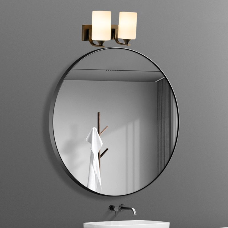 Clérachic two-light glass cylinder wall sconce mounted above a round bathroom mirror over a vanity sink.