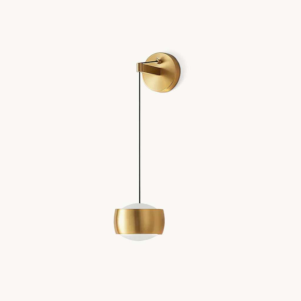 Brass Clérachic wall light on a plain white backdrop, a rounded cylinder shade hanging from a thin black cable and a round backplate.
