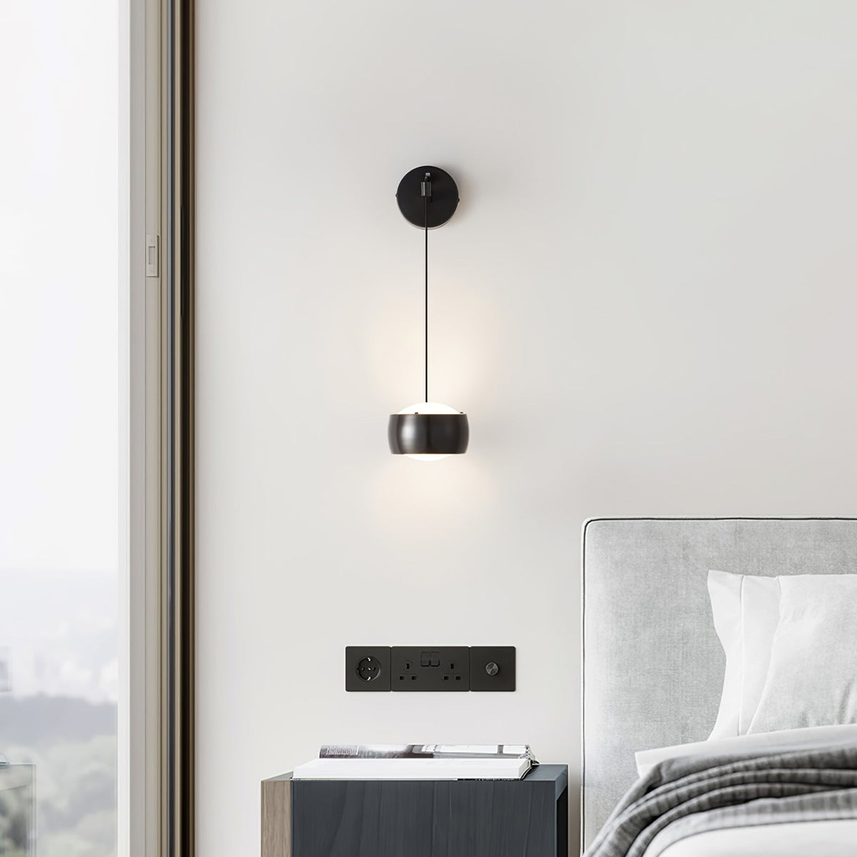 Black Clérachic wall light on a white wall beside a tall window, above a dark bedside cabinet and a grey headboard.