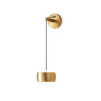 Brass Clérachic wall light on a white backdrop, shown full length with its cable, round backplate and small cylinder shade.
