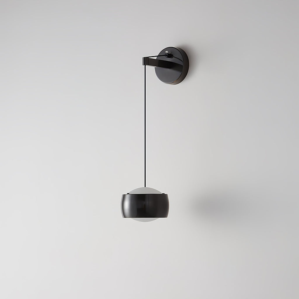 Black Clérachic wall light on a light grey wall, its glossy cylinder shade hanging below a round backplate on a thin cable.