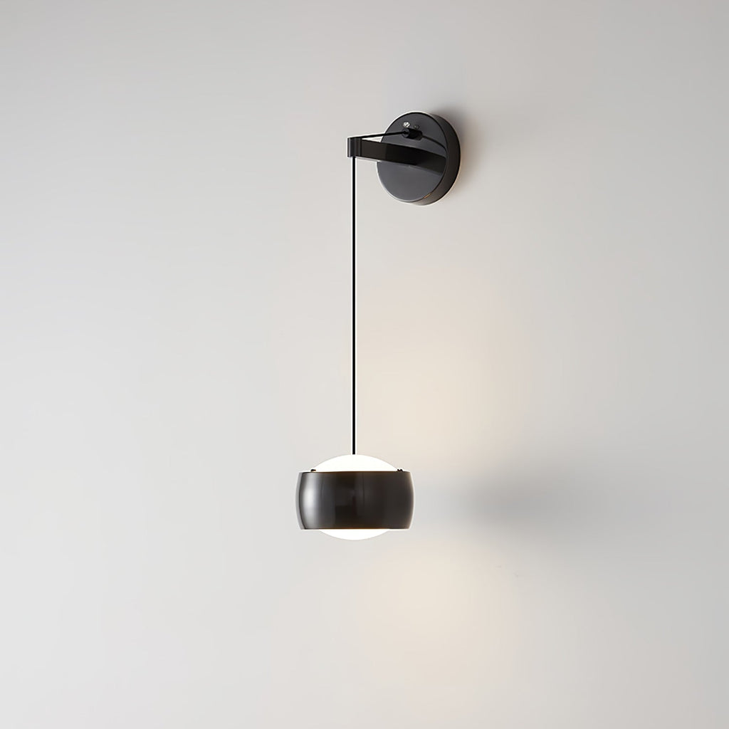 Close view of a black Clérachic wall light on a pale wall, light glowing around its shade and a soft shadow at the right.