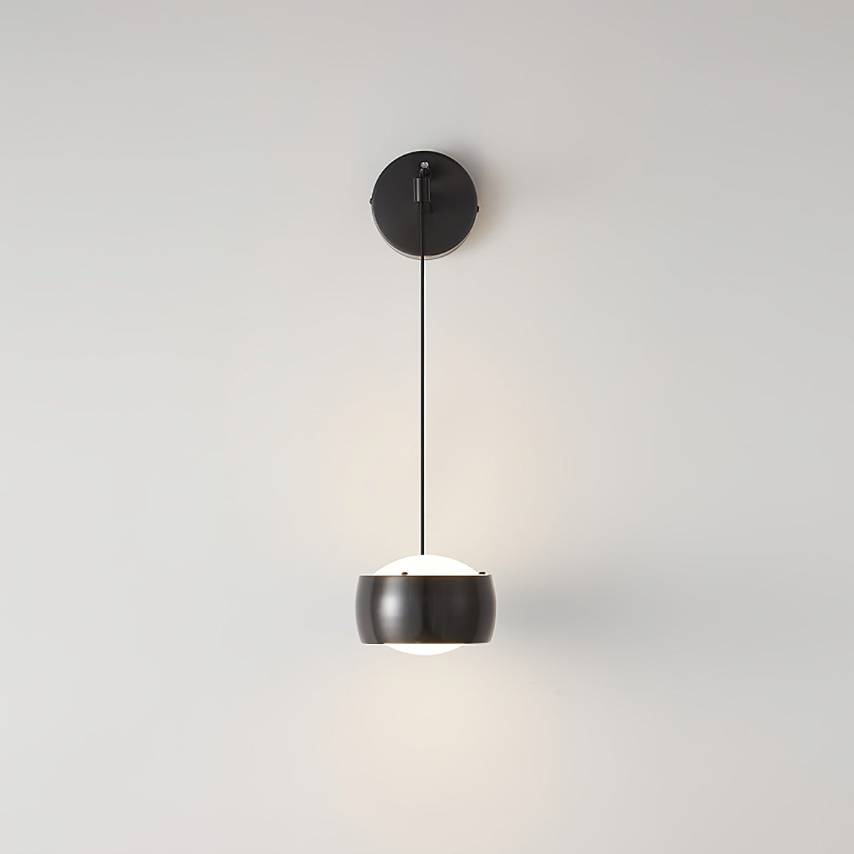 Front view of a black Clérachic wall light on a light grey wall, its shade lit white underneath and a round backplate above.